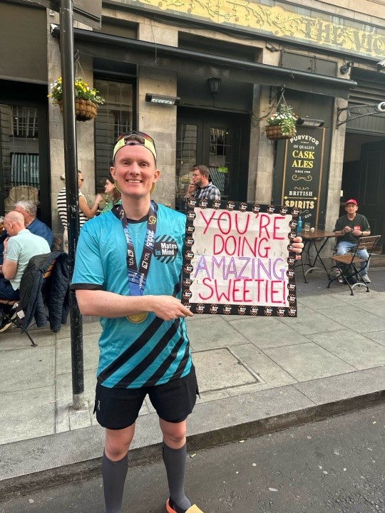 Ben holding a sign of support during 2025 London Marathon