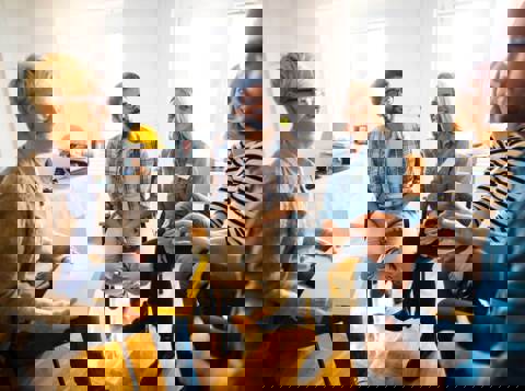 A group of people sitting in a circle in an office, talking about their mental health and checking in with each other