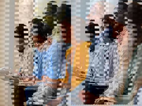 A diverse group of five employees sitting in a row, listening to a Mates in Mind presentation on mental health, and making notes