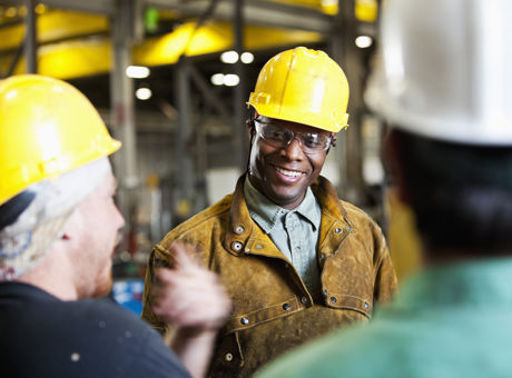 Three people wearing hard hats, standing inside a building that is under construction, they are talking about Mates in Mind